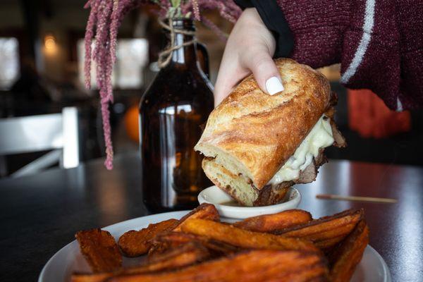 SOUTHERN DIP: House roast beef, thinly sliced, on a Le Petit Outre baguette with garlic aioli, and tomato jam, dipping cup of red-eye gravy.