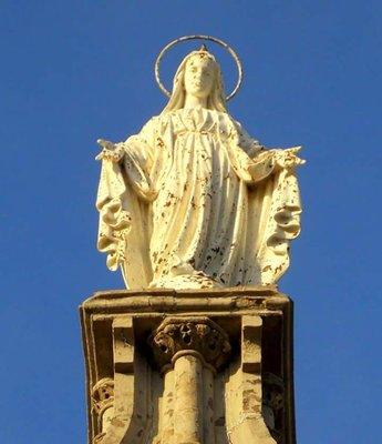 Virgin Mary at the top of the steeple.