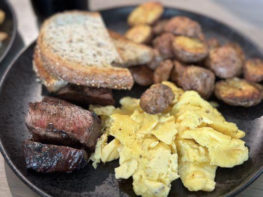 Steak and eggs scrambled with house potatoes and toast