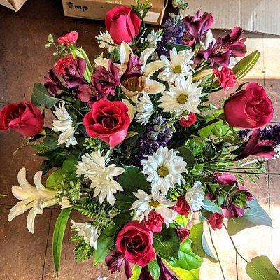 Top down look of mixed arrangement. Roses, Star Gazer Lilies, Daisy's.