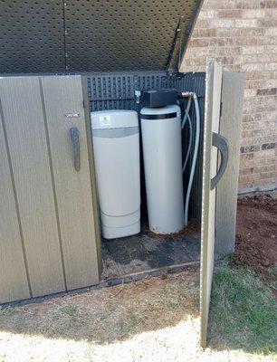 Water softener outside in equipment shed.