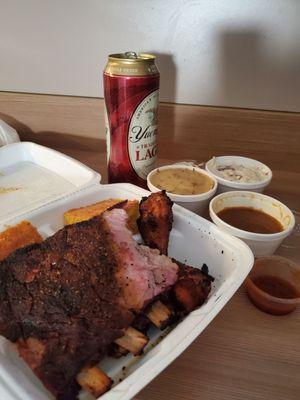 Quarter rack of ribs, smoked chicken wings, two pieces of corn bread, sides of mashed potatoes and gravy and coleslaw, and KC BBQ sauce.