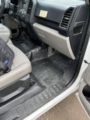 Passenger side footwell and seat filled with dirt and mud residue from the workers just wiping the weather mats down.