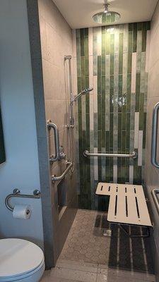 ADA Flip up seat in small shower  with grab bars for optimal use.