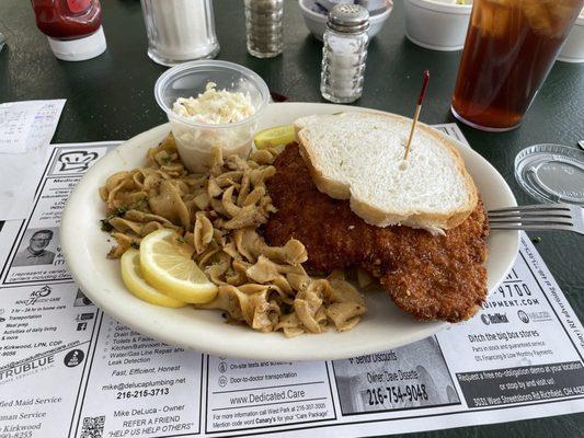 Weinerschnitzel sandwich with cabbage noodles and coleslaw.