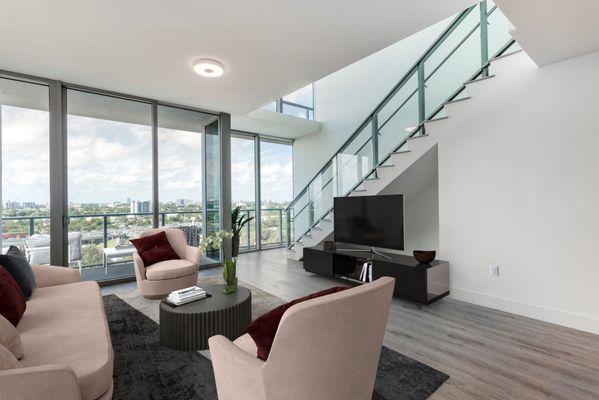 Spacious living room with floor to ceiling windows for ample natural light and wood plank style flooring at Lantower River Landing.