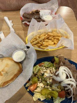 Open face gyro dinner and sausage sandwich with fries.