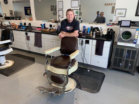 The owner with one of his classic barbershop chairs.