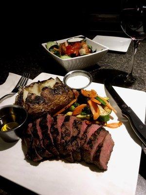 Grilled flat iron steak plate with sautéed vegetable and a baked potato, served with drawn butter and sour cream.