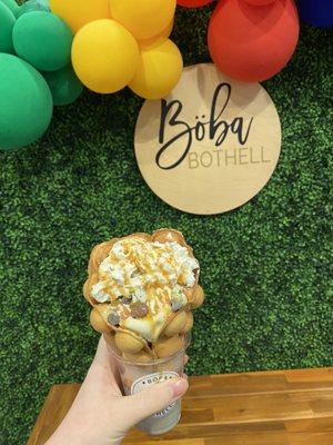 Bubble waffle cone with vanilla ice cream, mochi, chocolate chips, whipped cream and caramel drizzle.