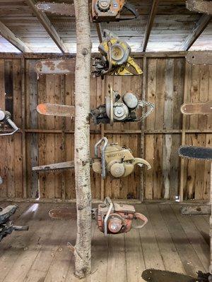 One tree trunk from a whole cabin full of logging tools embedded in tree trunks.