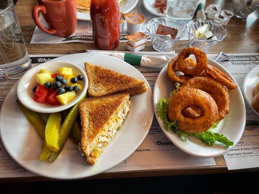 Tuna melt with fresh fruit, extra pickle, and an order of onion rings.