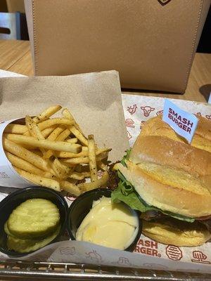 Bacon double smash burger with smash fries and pickles on the side