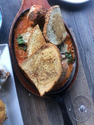 Very well-spiced meatball appetizer with a creamy tomato sauce, some spinach, cheese, and crunchy toast