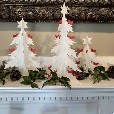 Hand crafted paper cut trees decorate the fireplace.