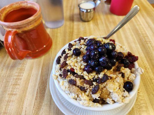 Oatmeal with blueberries, raisins, walnuts, brown sugar, milk and decaf coffee.