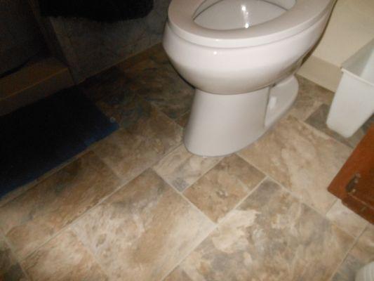 The new toilet and flooring in our other bathroom. This is how the caulking looked before Wickstrom "fixed" it, twice.