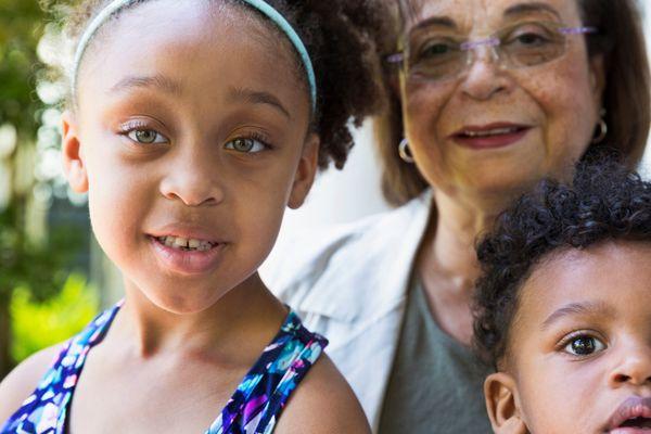 An elderly woman with her granddaughter and grandson taking a photo.