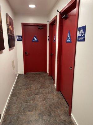 Hallway showing three individual bathrooms; all are gender neutral single-stall