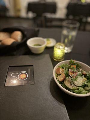 Salad in the front and bread basket in the back with the garlic oil.