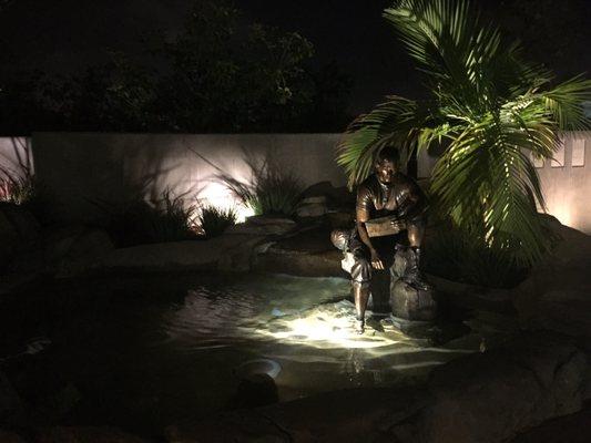 A bronze statue of Ernie Pinamonti by a reflecting pond reading a letter from home.