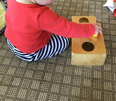 An infant friend using an object permanence box.