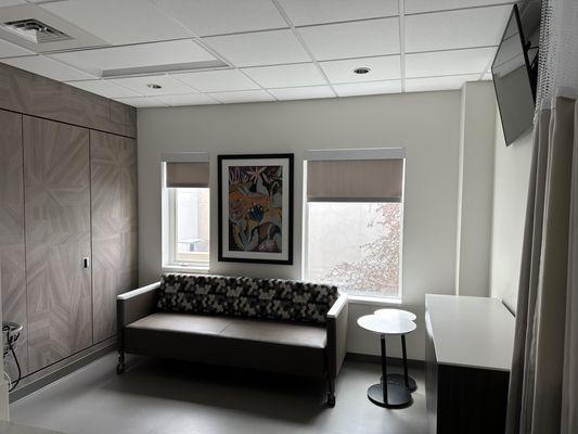 Living room inside the patients room including closet, sofa bed, nightstand, and TV