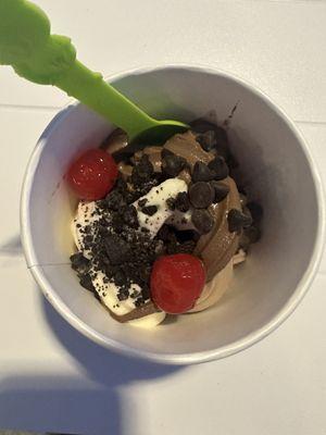 Vanilla mixed with chocolate yogurt with Oreo sprinkles on top and two cherries