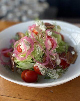 Wedge salad with candied bacon, pickled red onion, Roma tomatoes, and dill, topped with miso blue cheese dressing