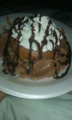 Dounght topped with whipped cream and chocolate served with ice cream