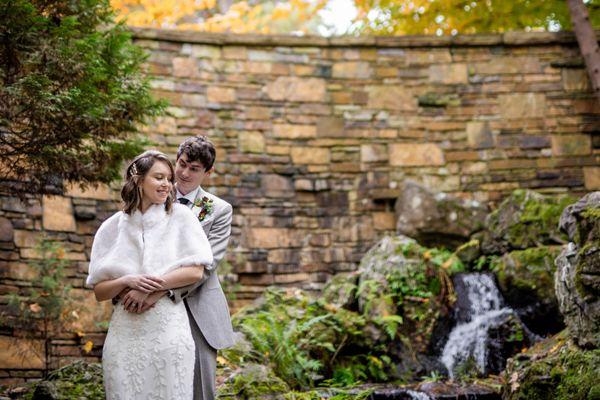 Romantic bride and groom embracing by a waterfall at Anthony Chapel in the lush Hot Springs National Park. Photo: Michele McCoy Photography