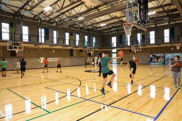 Pick-up basketball in the gymnasium. Members can walk the indoor track around the courts