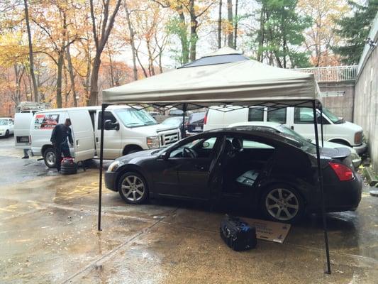 Tyrone hard at work repairing my car window in the rain.  Brought his own canopy since the job was being done outside.  Thanks Tyrone!