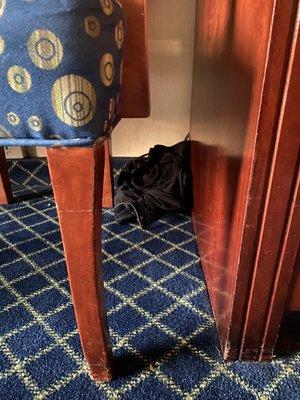 Clothes waded up in corner behind chair