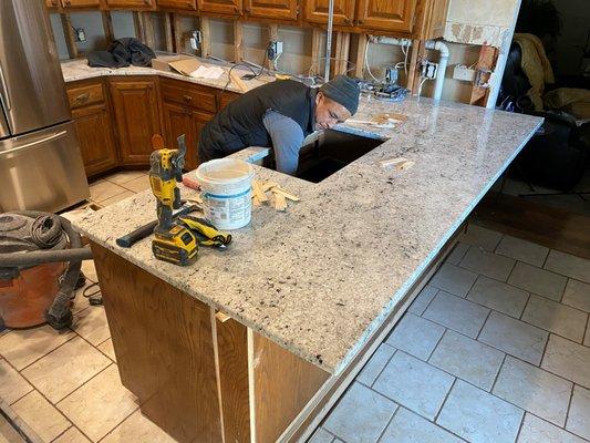 Installer shimming up granite countertop.