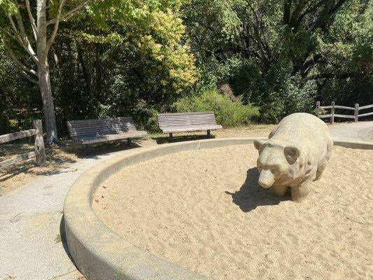 A sand pit with a bear in it.