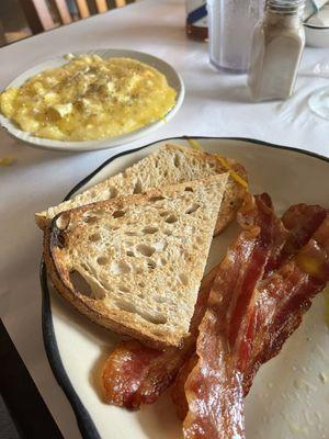 Two eggs over easy sourdough toast grits and bacon