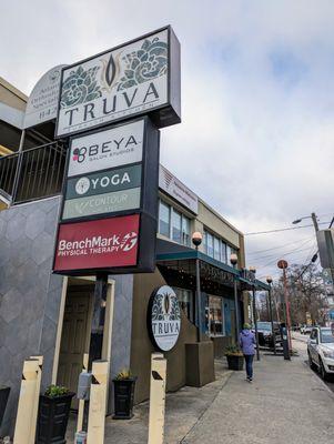 Outside. Storefront. Street sign for building. Dedicated parking lot on-site. You have to pay during certain hours.