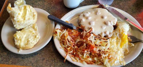 Chicken fried steak with sausage gravy, hash browns, and biscuit