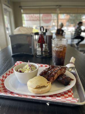 Pork ribs, homemade coleslaw, and a delicious dinner Roll with an ice cold Coca-Cola drink.