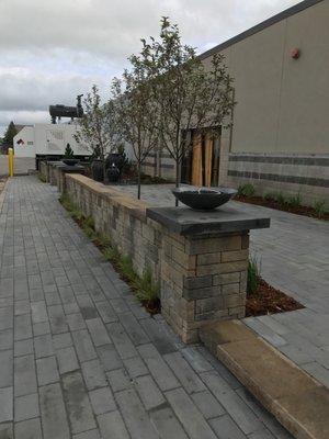 Commercial patio, pavers, freestanding wall with annual pots on pillars.