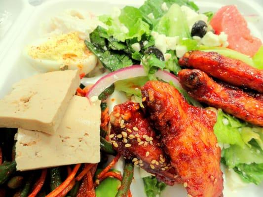 Box from the buffet:  marinated tofu, cold green beans, kim chee, cold spinach, sesame chicken wings, Greek salad, deviled egg