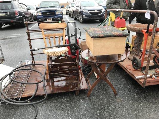 Upholstered stool, antique wooden furniture sitting in rain & puddles outside prior to being auctioned