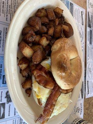 Bacon, egg and cheese bagel sandwich with home fries.