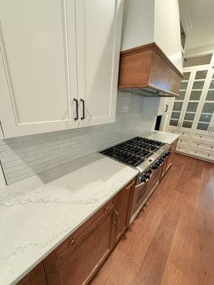 Kitchen with quartz countertop. Natural finish at bottom cabinets and white upper cabinets