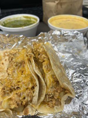 Potato, egg, chorizo, & cheese breakfast tacos on flour tortillas with chips, salsa, & queso in the background.