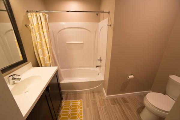 Wooden style floor tiles add character to this fully gutted and re-configured bathroom.  The integrated sink bowl makes for easy clean up!