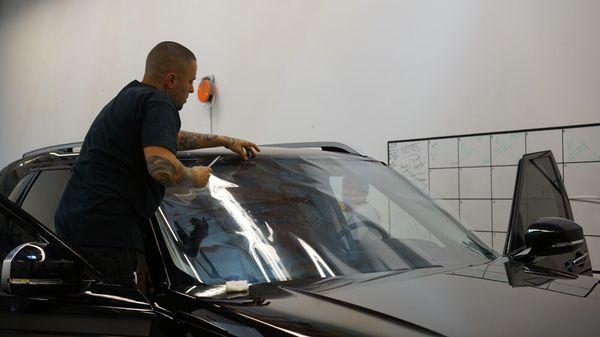 Beau precuts the film outside of vehicle to apply later to the inside of the windshield. (Prestige Photosync 75%)