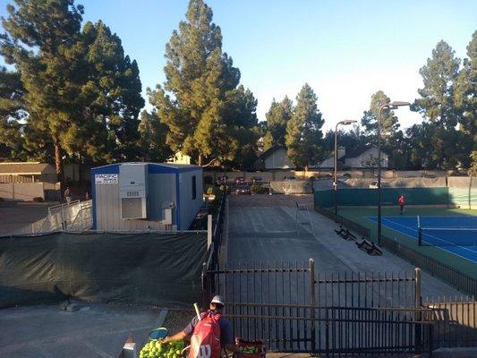 Trailer next to stadium court is for making court reservations and signing up for tennis classes.