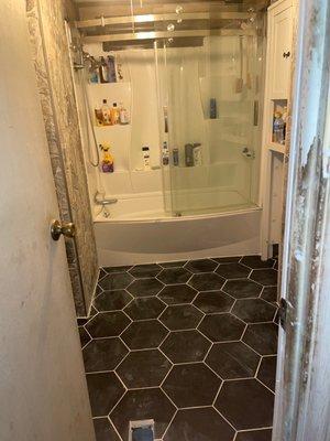 Porcelain floor tile with shower enclosure in background.